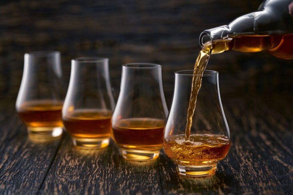Whiskey poured into a flight of Glencairn tasting glasses on a dark oak table